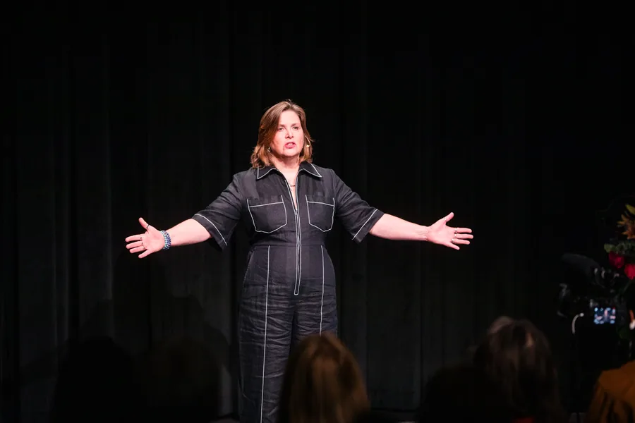 Theresa speaking to a room, arms open